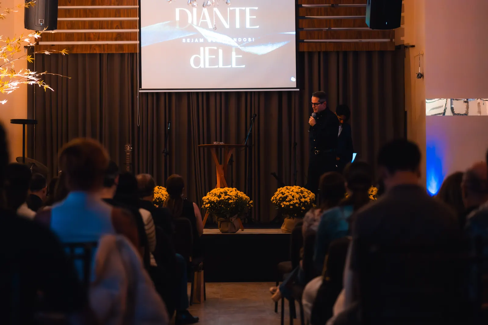 Evento na Marvelous Casa, com apresentação no palco, projeção e público sentado