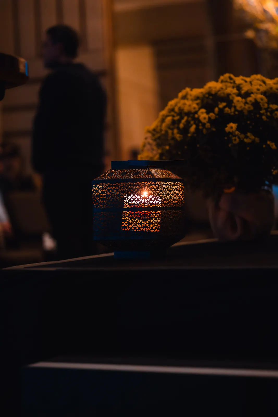 Lanterna acesa e arranjos de flores no palco, em luz baixa