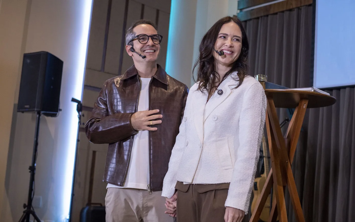 Dois apresentadores no palco da Marvelous Casa, com caixa de som ao fundo